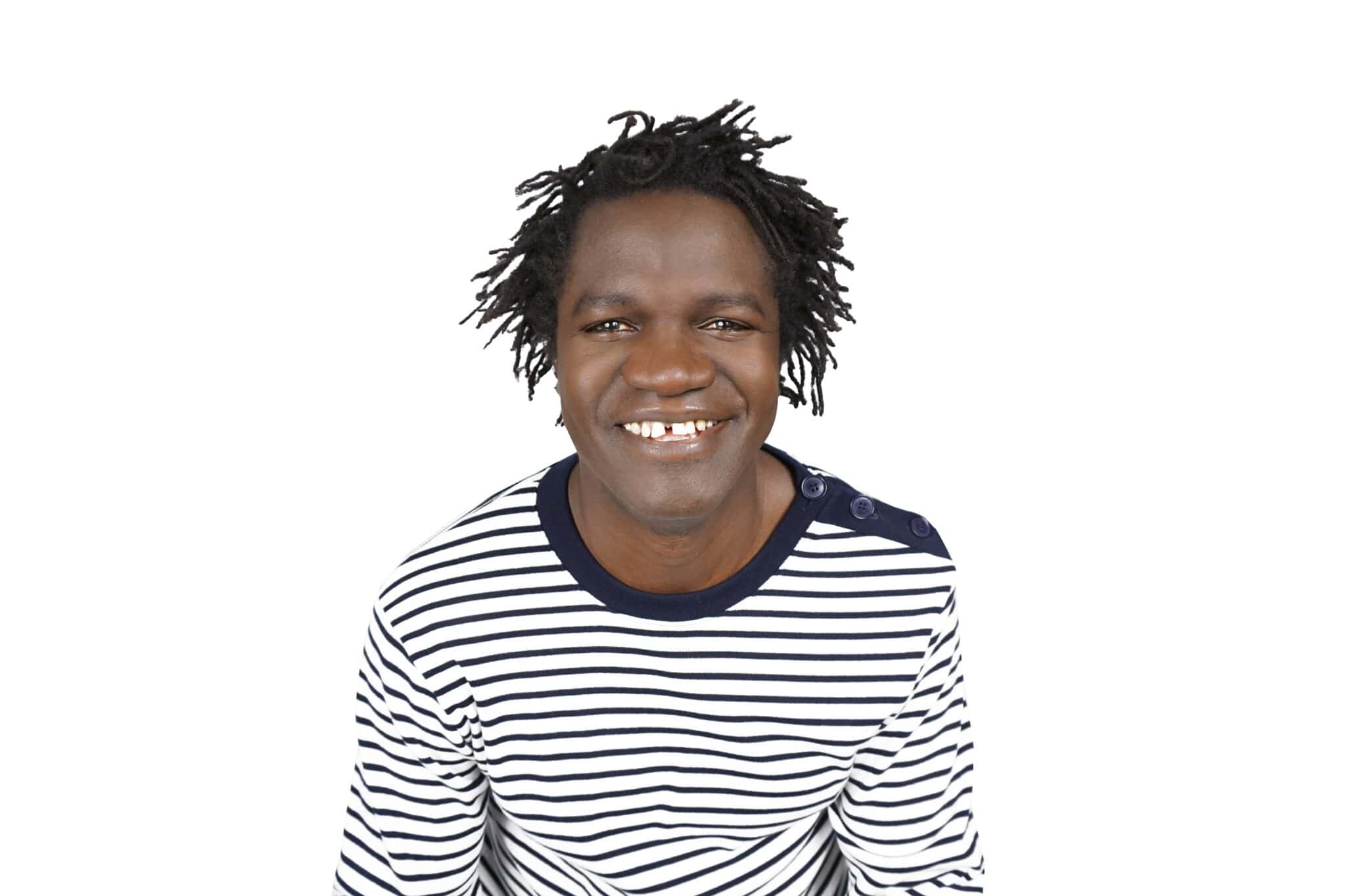 L’humoriste Boucar Diouf, souriant et portant un chandail rayé